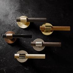 three brass and black door handles on a dark background