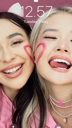 two girls with their faces painted pink and one has the word love on her face