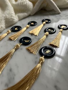 black and gold tassels are laid out on a marble countertop with white towels in the background