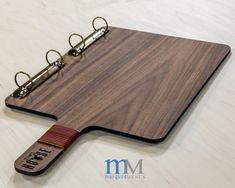 a wooden cutting board with metal clips attached to it and a note pad on the side