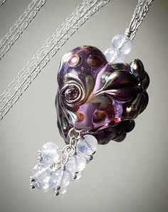 "Another GORGEOUS handmade glass pendant!  This purple \"blooming heart\" is so lovely with a silver glass swirl and a silver glass lily at the top.  Adding the icy pale Lavender Quartz \"pops\" the purple in the heart and completes the necklace beautifully.   The pendant hangs beautifully from an 18 inch Sterling Silver chain. I love this piece!  Modern, edgy, and lovingly handcrafted. Thank you for your interest! All metal components are .925 Sterling Silver All gems are genuine, AAA rated.  Handmade Artisan Glass Lampwork - NOT mass produced or sold commercially. Handmade, One of a kind Ready to ship This item comes in a gift box and is ready for gift giving. You will receive the exact item in this listing. Please send me a convo with any questions or special requests. Thanks!" Whimsical Silver Glass Jewelry, Whimsical Silver Czech Glass Jewelry, Whimsical Czech Glass Silver Jewelry, Whimsical Silver Jewelry With Heart Beads, Silver Glass Jewelry With Heart Charm, Bohemian Jewelry Earrings, Blooming Heart, Lampwork Bead Necklace, Opal Bangle