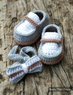 three crocheted baby shoes are laying on a piece of wood