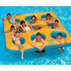 several children are floating on an inflatable raft at the swimming pool and having fun