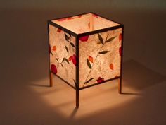 a lamp that is sitting on top of a wooden stand with flowers painted on it