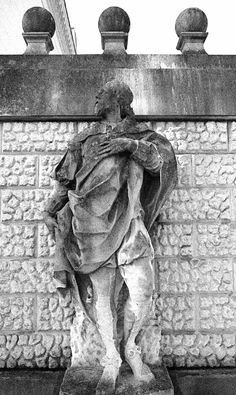 black and white photograph of a statue in front of a brick wall