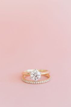 a close up of a diamond ring on a pink background