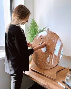 a woman standing in front of a wooden wheel with writing on it