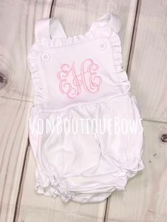 This white ruffled romper is so cute and comfy ! Perfect for summer and every day wear ! 100 % cotton, knit fabric (so soft!) Elastic in leg opening Snaps in crotch  Buttons at shoulder PERSONALIZATION CAN BE IN ANY COLOR ! (light pink shown with vine monogram - hot pink shown in Fancy monogram) Please leave the name or full name (for monogram) in the notes to seller section during checkout, along with thread color  Other designs available ! Please message me to start your custom order :) any ot Spring Cotton Bubble Romper With Ruffled Straps, Cute Bubble Romper With Ruffled Straps For Summer, Cute Summer Bubble Romper With Ruffled Straps, Spring Bubble Romper With Ruffled Straps, Cute Bubble Romper With Ruffle Hem For Spring, Cute Spring Bubble Romper With Ruffle Hem, Cute Cotton Bubble Romper With Ruffle Hem, Cotton Jumpsuits And Rompers With Ruffles, Cotton Ruffle Onesie For Playwear