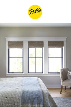 a bedroom with two windows and a bed in front of the window has a yellow hello sign above it