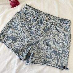 a pair of denim shorts on top of a white sheet with a tassel hanging from the side