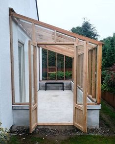 an open door leading into a small garden area with plants in the back ground and a bench on the other side