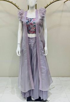 A sharara set in a refined lavender hue, tastefully designed in an Indo-Western style to achieve a stunning aesthetic. This three-piece ensemble comprises a blouse, palazzo pants, and a full-length shrug, ensuring a distinctive look. The spaghetti-sleeved blouse is adorned with intricate floral embroidery in multiple colors, enhancing its overall elegance. The included plain sharara pants feature a voluminous cut. The soft organza shrug is complemented by mirror lace detailing, while ruffle slee Plain Sharara, Organza Shrug, Mirror Lace, Stunning Aesthetic, Sharara Pants, Outfit Design, Sharara Set, Whatsapp Message, Indo Western