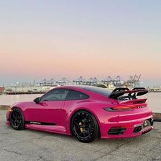 a pink sports car parked in front of a body of water