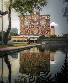 a person walking on the side of a body of water next to a large building