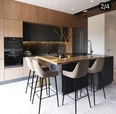 a kitchen with an island and bar stools next to the counter top, along with two chairs