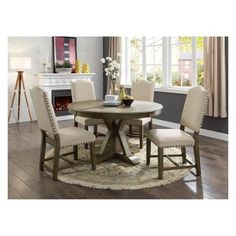 a round dining table with four chairs and a fire place in the backround