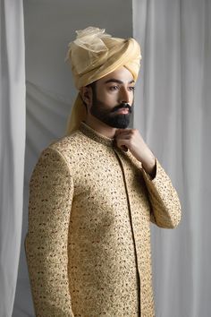 Discover the timeless elegance and regal charm of our Collar Detail Gold Sherwani. Made from pure atlas material, this sherwani features exquisite hand-embroidered jal work of resham, zardozi, Swarovski stones, and dabka. Complete with a jamawar kula (turban) and silk inner kurta pajama, this resplendent piece is perfect for any special occasion. Elevate your style with this luxurious and sophisticated sherwani. 4-Piece Suit Raw Silk Naqshi Bandhgala For Traditional Ceremonies, Gold Sherwani With Intricate Embroidery In Raw Silk, Raw Silk Bandhgala With Intricate Embroidery For Traditional Ceremonies, Ceremonial Raw Silk Sherwani With Naqshi, Gold Sherwani With Resham Embroidery And Kundan, Ceremonial Naqshi Sherwani In Raw Silk, Gold Traditional Wear With Naqshi Drape, Raw Silk Bandhgala With Resham Embroidery, Traditional Raw Silk Sherwani With Intricate Embroidery