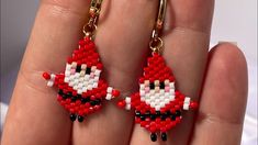 a pair of red and white beaded earrings on a person's hand