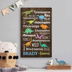 a wooden sign with dinosaurs on it next to a teddy bear and other toy animals