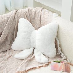 a white stuffed animal laying on top of a bed next to a book and pillow