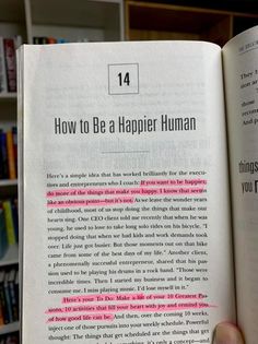 a person holding up a book in front of a bookshelf full of books