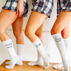 three women in short shorts and knee high socks are standing on a wooden floor with their legs crossed