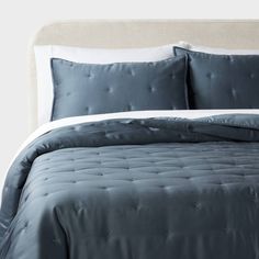 a bed with blue comforter and white pillows