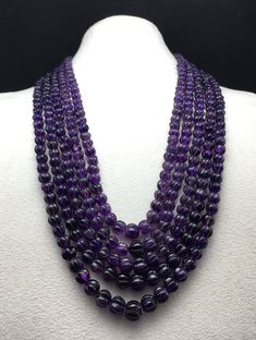 three strands of purple glass beads on a white mannequinl neckpieces