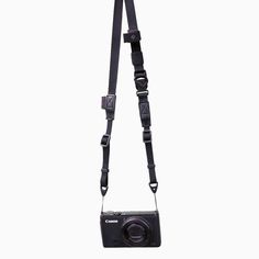 a black camera strap attached to a digital camera on a white background with no one around it