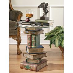 a glass table topped with books next to a chair and potted plant on top of a hard wood floor