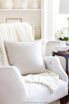 a white chair sitting in front of a table with flowers and vases on it