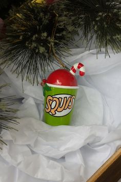 a green cup with a candy cane in it sitting on top of a white sheet