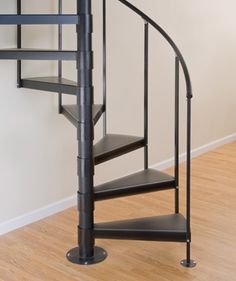 a black spiral staircase in an empty room