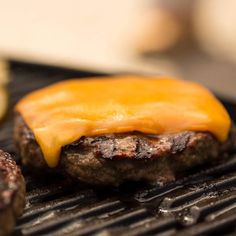 a hamburger with cheese on it sitting on top of a grill