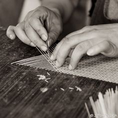 two hands are working on an object with needles and thread in black and white photo