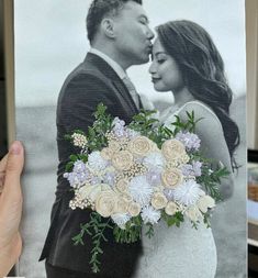 a photo of a bride and groom is being held up by a person holding a bouquet of flowers