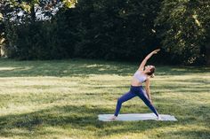 a woman doing yoga on a mat in the grass