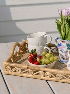 a tray that has some flowers and fruit in it on top of a wooden table