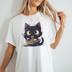 This Noodle Cat T-Shirt is perfect for cat lovers and foodie enthusiasts. The black color and cute design give off a fun and quirky vibe, making it a great addition to your casual wardrobe. Whether you're relaxing at home or out with friends, this shirt is sure to bring a smile to your face. Ideal for cat lovers and those who enjoy quirky fashion statements. Perfect for casual wear, lounging, or a fun night out. Product features - Made from durable and smooth fabric - Classic fit with crew neckl Black Kawaii T-shirt With Funny Print, Cute Black T-shirt With Cat Design, Funny Black T-shirt With Cat Design, Funny Black Top With Cat Design, Funny Black Cat Design Top, Foodie Lover, Cat Dad Shirt, Cat Apparel, Lover Clothes