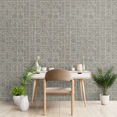 a chair and table in front of a wall with a pattern on it, next to two potted plants