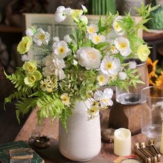 a vase filled with white flowers sitting on top of a wooden table next to candles