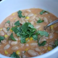 a white bowl filled with beans and cilantro on top of a wooden table