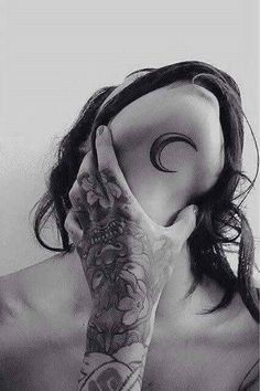 a woman with tattoos covering her face and holding her hand up to her face while looking at the camera