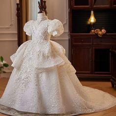 a white dress is on display in a room with wooden flooring and wall decorations