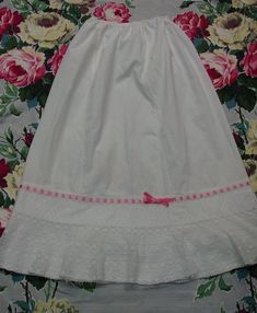 This is a darling antique petticoat. It is white cotton and measures 31" in length and the waist has elastic which is 22" but would extend to 24". It is very beautiful at the bottom edge with a row of lace that has a pink ribbon winding through it. Below that is a row of embroidered trim and then rows and rows of delicate lace. There is another plain ruffle underneath that has a tiny narrow trim of lace, which has a few small missing areas. The petticoat is in excellent condition with no spots or holes and has been recently washed and pressed. I combine shipping and am happy to provide a shipping quote to international shoppers. Thanks for visiting... Embroidered Trim, Lace Ruffle, Ribbon Trim, Cotton Lace, Pink Ribbon, Petticoat, White Cotton