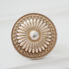 an antique brass door knob with beaded design on the front and sides, sitting on a white surface