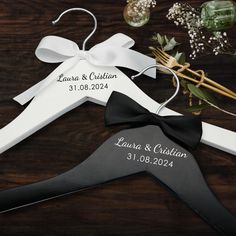 a wedding hanger with a black and white bow on it, next to flowers