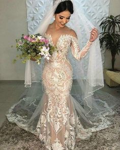 a woman in a wedding dress holding a bouquet and posing for the camera with her veil over her head