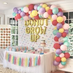 a dessert table with balloons and confetti on the wall behind it that says donut grow up