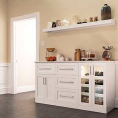 a kitchen with white cabinets and shelves filled with dishes on top of each cabinet,